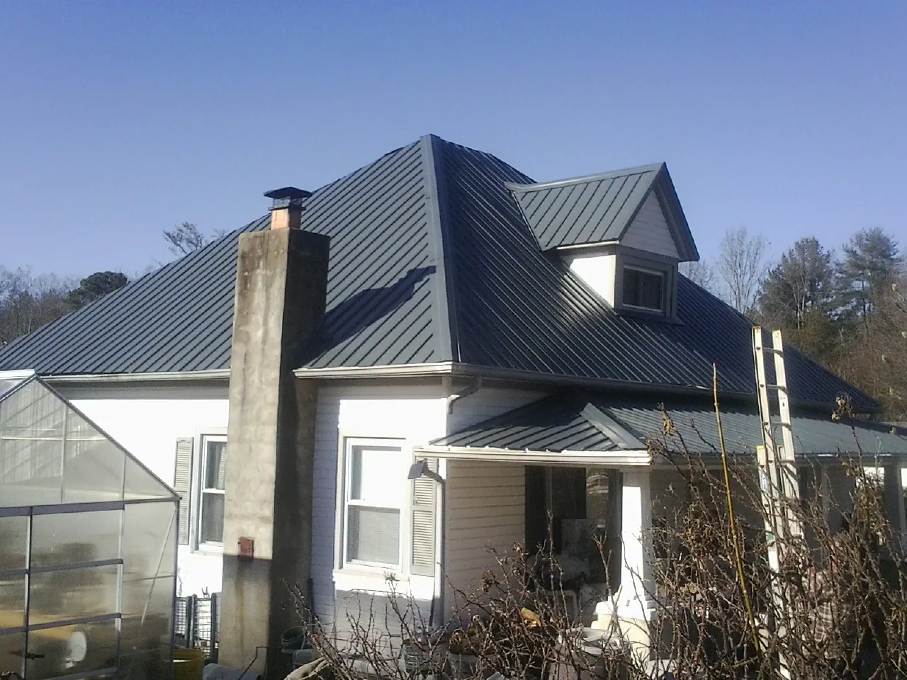 Dark blue standing seam metal roof on a white farmhouse with dormer — Slate & Tile Roof Repair by Roofing Brothers in Elkhorn City