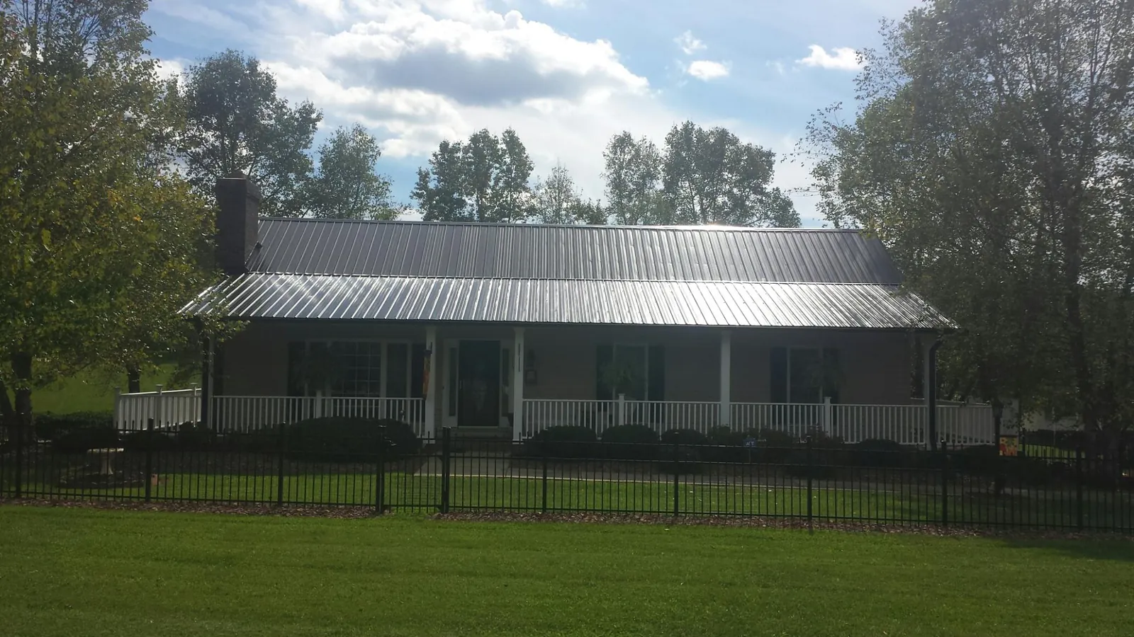 Gray metal roof on a brick ranch with a full width front porch — Gutter Guard Installation work by our crew in Elkhorn City