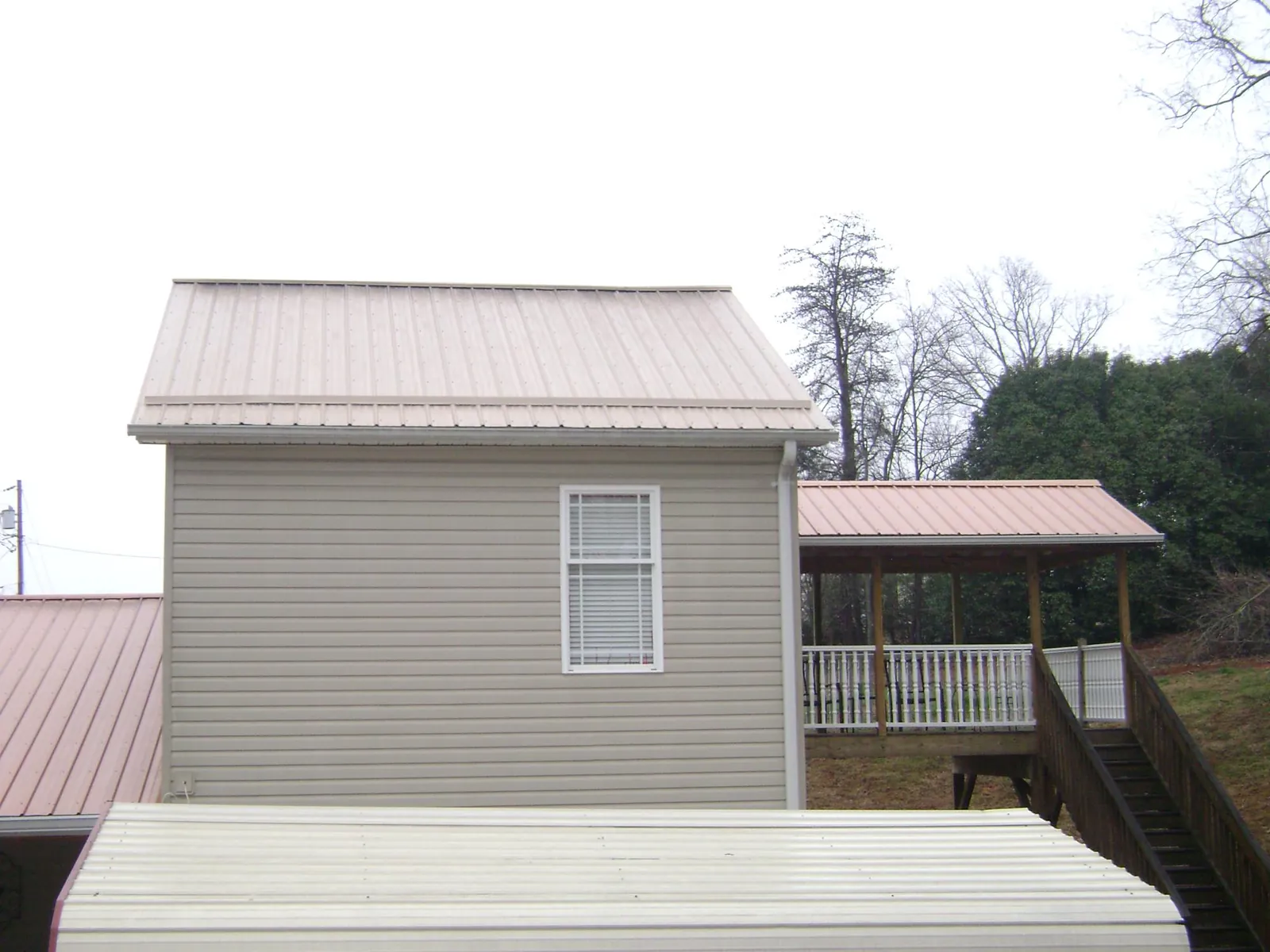 Tan metal roofs on a two story addition and attached porch, from a Roof Replacement job in Elkhorn City