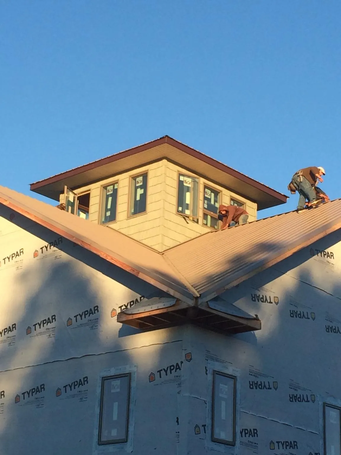 Roofers working around a rooftop cupola on a new metal roof at sunset — Roof Waterproofing in Elkhorn City by Roofing Brothers
